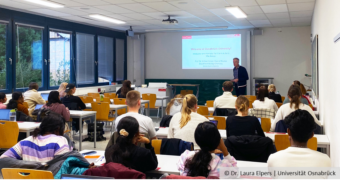 View from behind into a seminar room full of students. At the front is the Dean of Studies, Prof Michael Hensel.