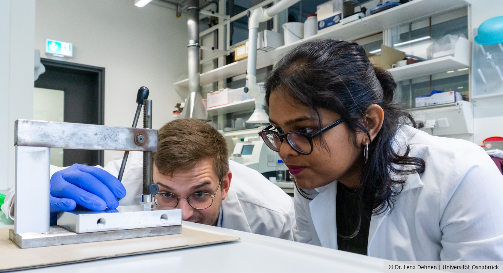 Zwei Personen im Labor betrachten ein wissenschaftliches Instrument.