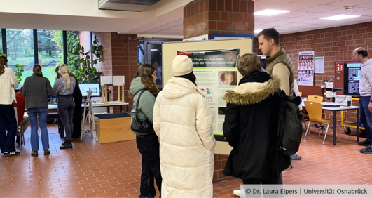 Schülerinnen und Schüler stehen im Foyer des Biologie-Gebäudes, im Hintergrund sind Mitmach-Stände zu erkennen.